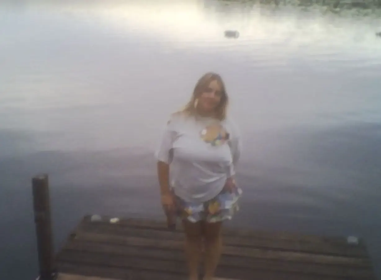 A kid standing on a dock in front of a lake